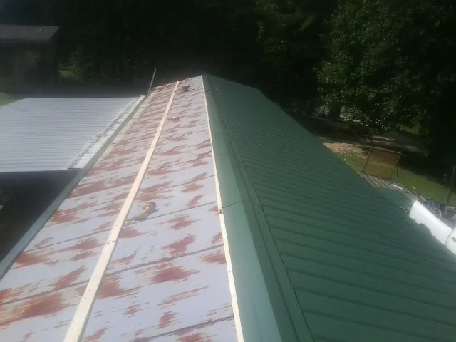 Old rusted panels beside newly installed green metal roofing — Wind Damage Roof Repair by Roofing Brothers in Palm Coast