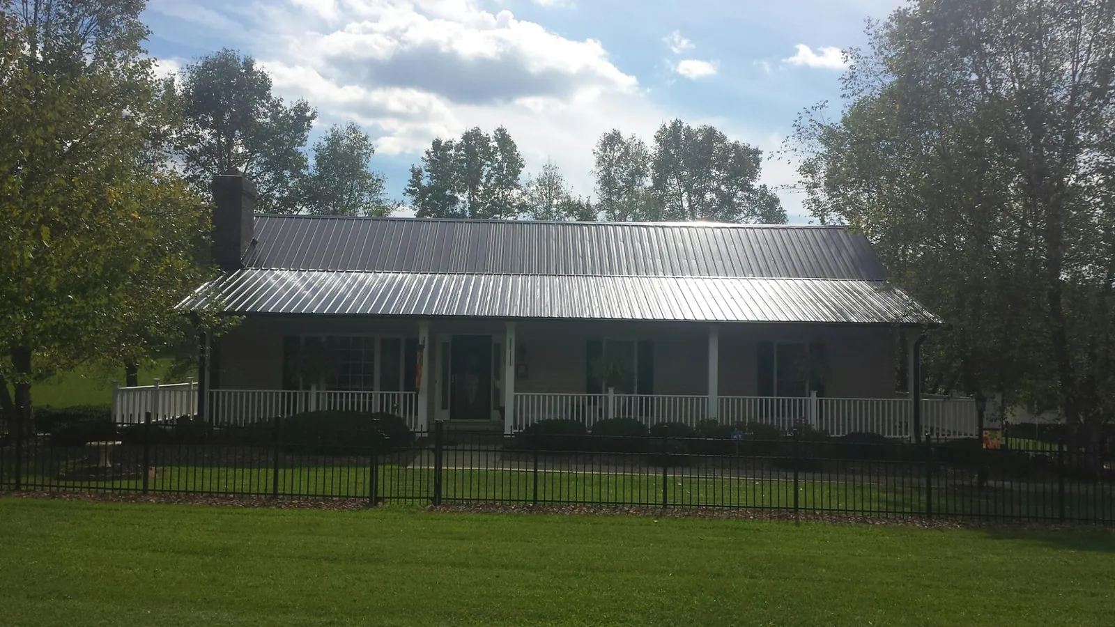 Gray metal roof on a brick ranch with a full width front porch — Gutter Guard Installation work by our crew in Palm Coast