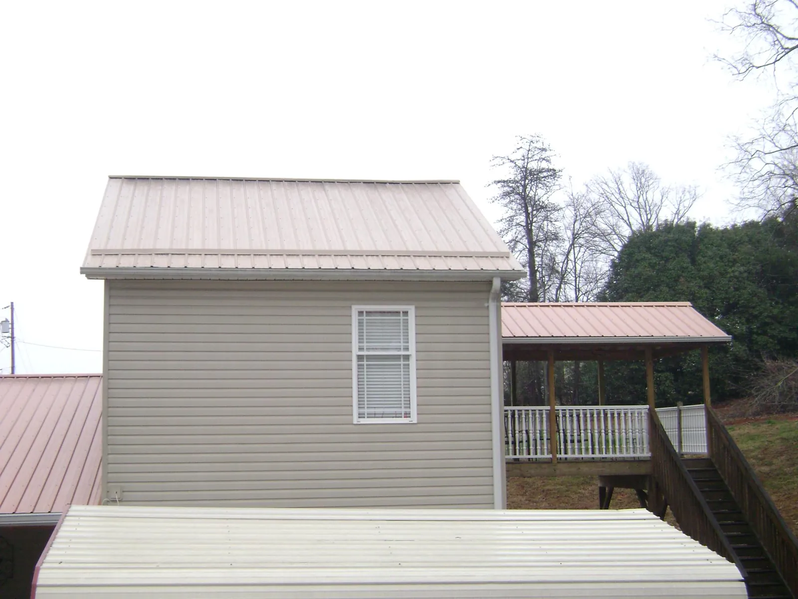 Tan metal roofs on a two story addition and attached porch, from a Roof Replacement job in Palm Coast