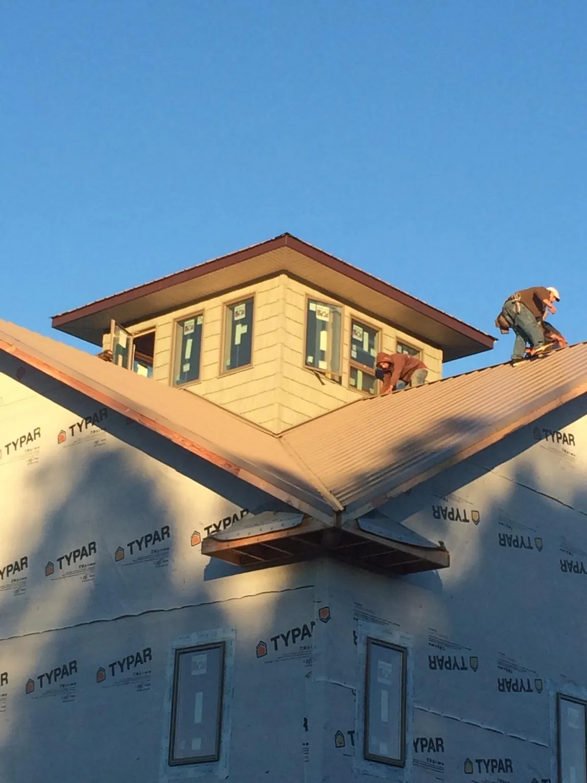 Roofers working around a rooftop cupola on a new metal roof at sunset — Roof Waterproofing in Palm Coast by Roofing Brothers